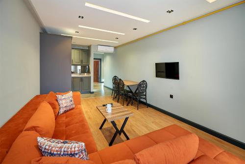 Sofyapart في Soğuksu: غرفة معيشة مع أريكة برتقالية وطاولة