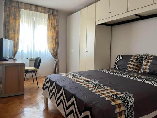een slaapkamer met een bed, een bureau en een televisie bij Domestico apartment in Rijeka