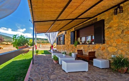 a patio with white chairs and a stone building at CR El Portezuelo Boutique Experience in Fuentelabrada de los Montes