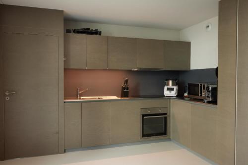 cocina con armarios marrones y fregadero en NYON - Appartement meublé tout confort en Nyon