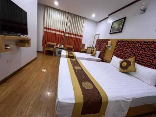 a hotel room with two beds and a flat screen tv at Khach sạn Vân Nam in Hanoi