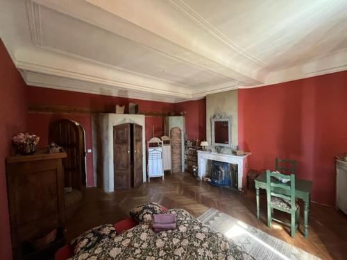 een slaapkamer met rode muren, een bed en een open haard bij Chambre avec vue in Saignon
