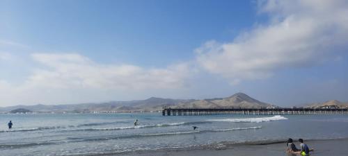 people on the beach with a pier in the water at Bungalows Cerro Azul in Cerro Azul