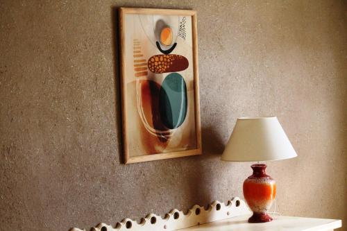a lamp on a table with a picture on the wall at Szwajcaria Mazurska in Zawady Oleckie