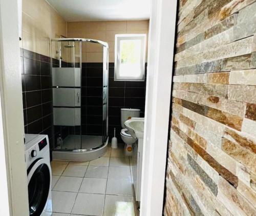 a bathroom with a washer and dryer next to a brick wall at Radovanovic in Matulji