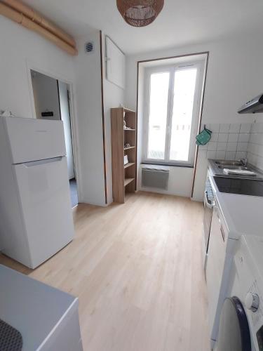 une cuisine avec un réfrigérateur blanc et une fenêtre dans l'établissement La Maison de la Plage, à Arromanches-les-Bains