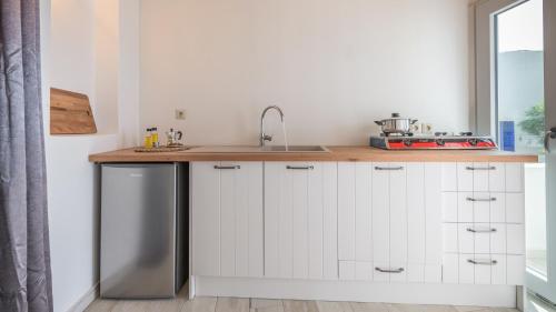 cocina con armarios blancos y lavavajillas de acero inoxidable en Casa del Mar Milos en Kástron