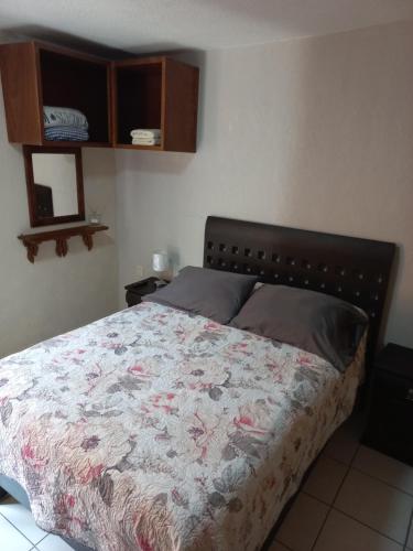 um quarto com uma cama com uma colcha em Agradable y cómodo departamento a 5 minutos del aeropuerto em Cidade do México