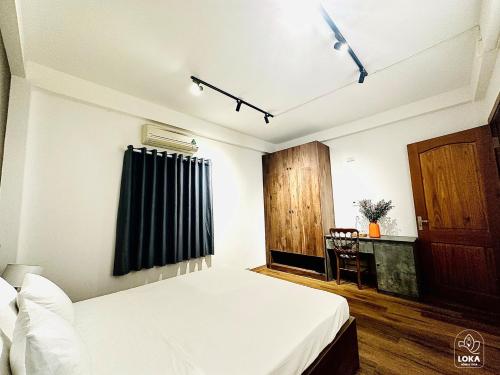 a bedroom with a white bed and a black curtain at Loka Home & Yoga in Da Nang