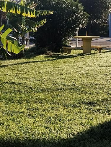 a park with a bench and a table in the grass at Pousada Atlântica stay home in Tramandaí