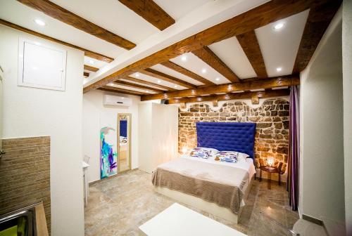Un dormitorio con una cama azul y una pared de piedra en Apartment Genius Loci, en Split