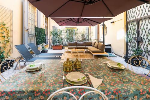 une terrasse avec une table, un canapé et un parasol dans l'établissement Fossalta Home, in the heart of the Historical Center, à Bologne