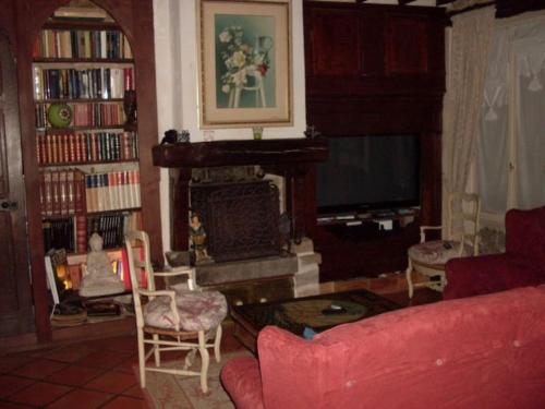 uma sala de estar com um sofá vermelho e uma lareira em Ambiance Milly la Foret em Milly-la-Forêt