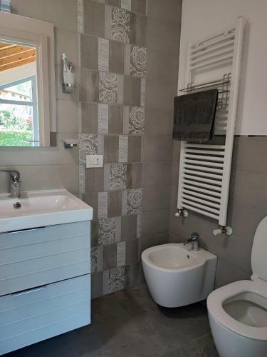 un baño con lavabo, inodoro y espejo en Olia House, en Olginate