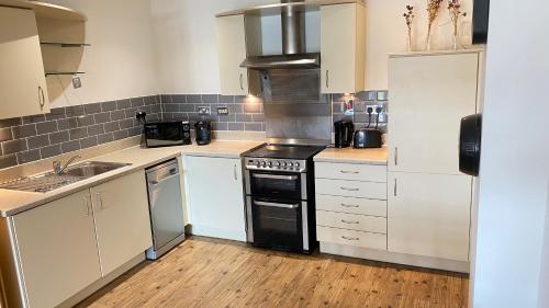 een keuken met witte kasten en een zwarte oven bij City Centre Apartment Jewellery Quarter in Birmingham