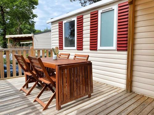 a wooden table and chairs on a deck with a house at MOBIL HOME 6 personnes Cap Ferret in Lège-Cap-Ferret