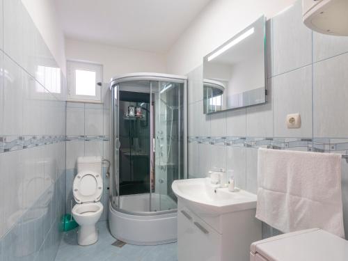 a white bathroom with a toilet and a sink at Apartments L&L in Podstrana