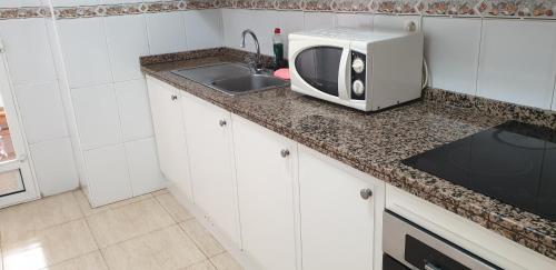 a kitchen with a sink and a microwave on a counter at Apartamento Salamanca in Guardamar del Segura