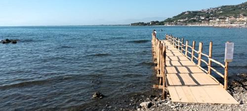 a wooden pier in the water with a person on it at Hotel Mare in Agropoli