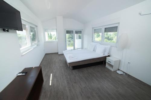 a white living room with a couch and windows at Villa HS in Mostar