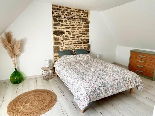 une chambre avec un lit et un mur de briques dans l'établissement maison secteur Mont St Michel, à Reffuveille