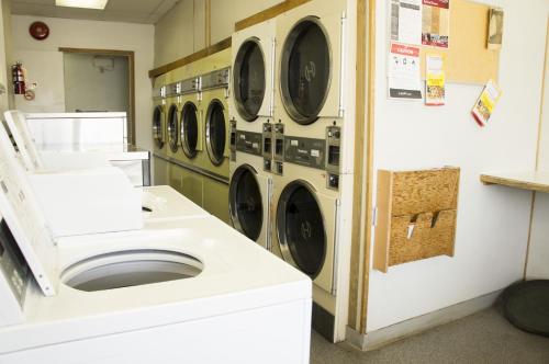 a laundry room with a row of washers and dryers at Lazy J Motel in Claresholm