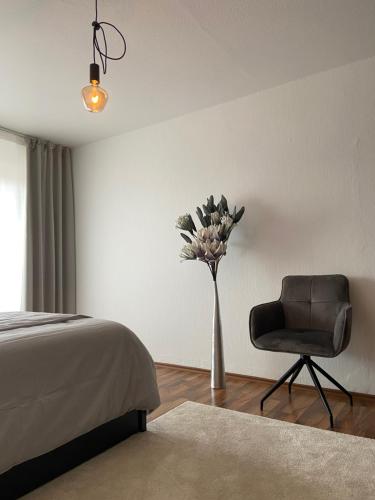 a bedroom with a vase of flowers and a chair at CHALET_3 Design Appartments in Waldbüttelbrunn