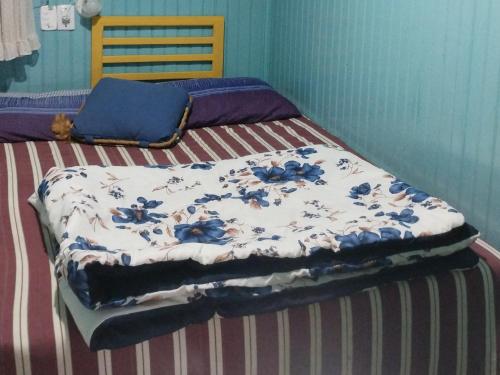 a bed with a blue and white blanket on it at Pousada Atlântica stay home in Tramandaí