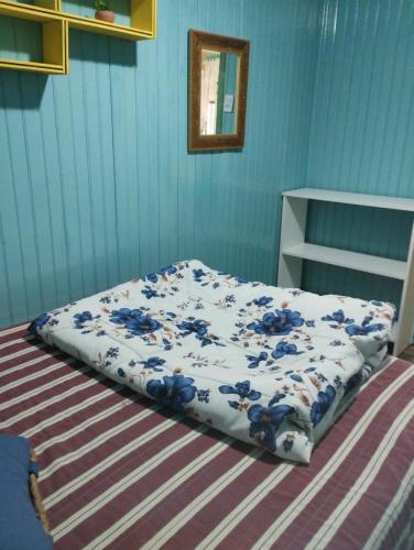 a bed in a bedroom with a blue wall at Pousada Atlântica stay home in Tramandaí