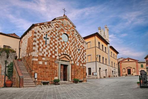 a brick building with a cross on top of it at Nel centro storico di Trequanda in Trequanda