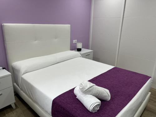 a bed with a pair of white shoes on a purple blanket at MIRAGREDOS CASA RURAL in Mombeltrán
