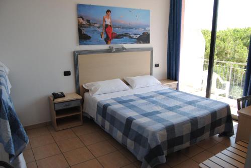um quarto com uma cama com um cobertor xadrez e uma janela em Hotel Capriccio em Cervia