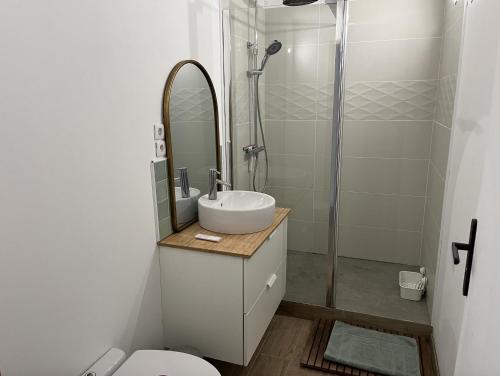 uma casa de banho branca com um lavatório e um chuveiro em Gîte à 3 minutes à pied de la mer em Bernières-sur-Mer