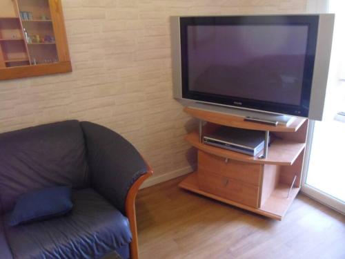 ein Wohnzimmer mit einem Sofa und einem TV auf einem Stand in der Unterkunft La Saléve in Agen