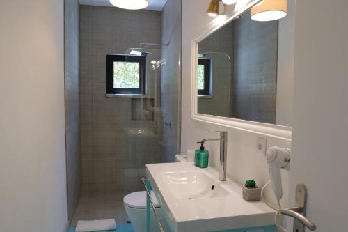 uma casa de banho com um lavatório e um chuveiro com um espelho. em PH in Aroeira Lisbon - Beach & Golf em Aroeira