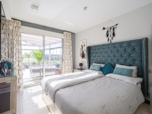 1 dormitorio con 1 cama grande y cabecero azul en Salobre Villas VistaGolf, en La Playa de Arguineguín