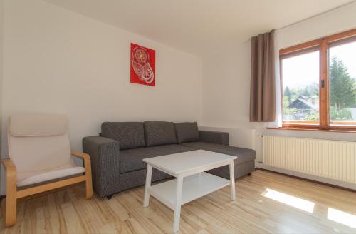 ein Wohnzimmer mit einem Sofa, einem Tisch und einem Stuhl in der Unterkunft Nad tunelom apartment Bohinj in Bohinj