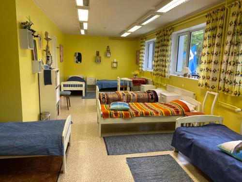 Habitación con varias camas en una habitación con paredes amarillas. en Torgu Royal Guesthouse en Iide