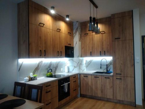 een keuken met houten kasten, een wastafel en een fornuis bij Uniejów Apartament in Uniejow