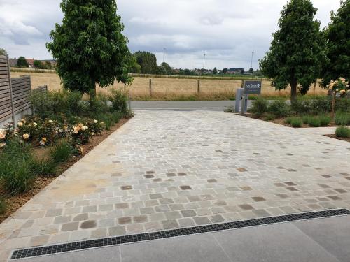 a stone walkway in a park with trees and flowers at Vakantiewoning De Bles in Avelgem