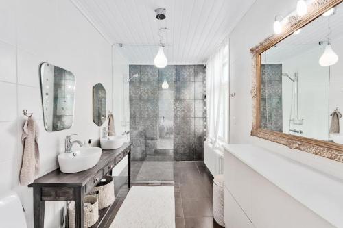 een witte badkamer met 2 wastafels en een spiegel bij Villa Degerby - 330m2 Lux Manor w/Heated Pool, Spa in Degerby
