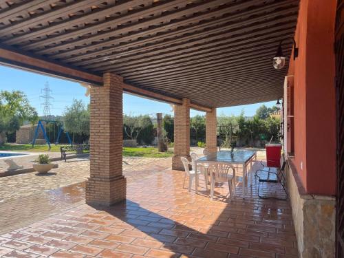 a patio with a wooden pergola with a table and chairs at La Estacada in Lora del Río