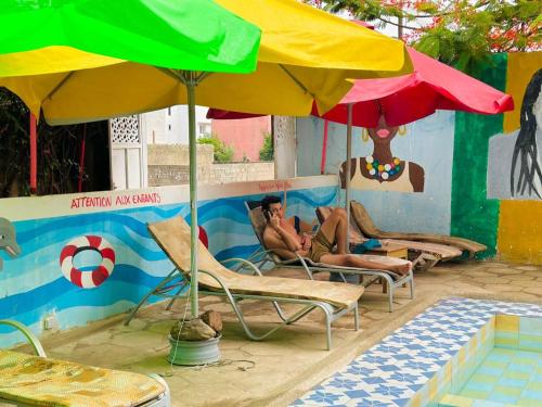 a couple of men laying in chairs under an umbrella at Auberge Africa Thiossane in Saly Portudal