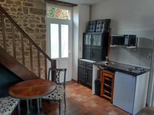 a kitchen with a staircase and a table and a microwave at Sept-Forges Gite in Sept-Forges