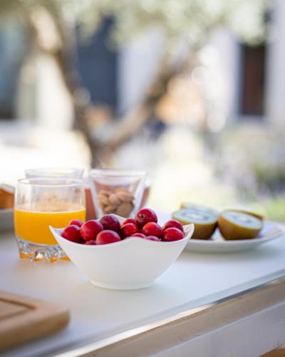 a table with a bowl of fruit and a glass of orange juice at LES LODGES TAIZEN, séjour SPA- sans enfants in Saint-Cannat