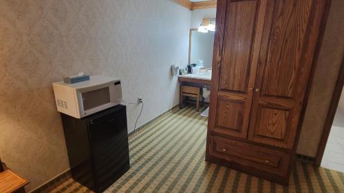 a room with a microwave on top of a refrigerator at Ramada by Wyndham Saginaw Hotel & Suites in Saginaw