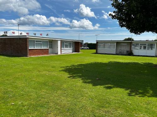 un gran patio con dos edificios y un árbol en 2 Bedroom Chalet Close to Beach, en Hemsby