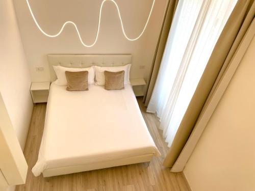 a bedroom with a white bed with pillows and a window at Casa Manzoni LOFT MXP Town Center in Gallarate