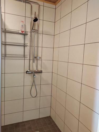 La salle de bains est pourvue d'une douche avec un tuyau et de carrelage blanc. dans l'établissement Maalaistalon päätyhuoneisto Merikarvialla, à Tuorila