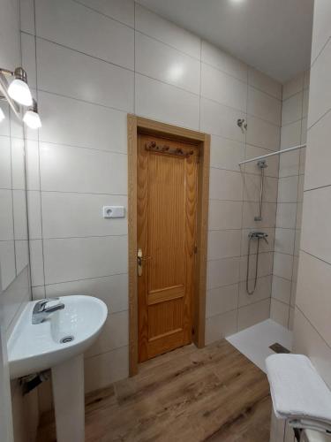 a bathroom with a sink and a wooden door at Hostal Miralva in Madrid